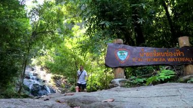 Ton Chongfa Şelalesi girişindeki erkek turist. Khao Lak Amphoe Takua Pa Phang Nga Tayland 'daki bilgi panolarına hoş geldiniz..