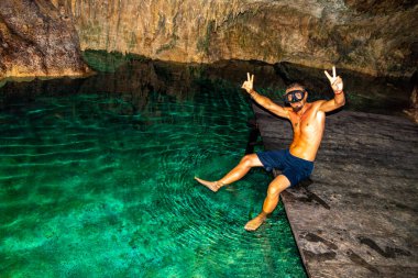 Erkek tur rehberi, Tulum Quintana Roo Mexico 'daki Yaxmulito mezarlığında turkuaz yeşil suda yüzüyor ve şnorkelle yüzüyor..