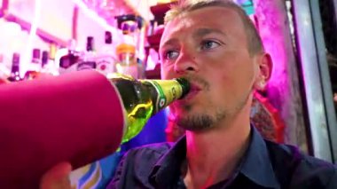 Yakışıklı turist Chang Leo birasını gece pazarında içiyor Bang Niang Market Chong Fah, Khao Lak Amphoe Takua Pa Phang Nga Tayland, Güneydoğu Asya.