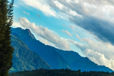 Dağ manzarası dağları yeşil tarlalar orman bulutları ve Alpler 'deki mavi gökyüzü Tyrol Avusturya.