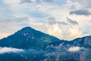 Dağ manzarası dağları yeşil tarlalar orman bulutları ve mavi gökyüzü Alpler Vorarlberg Avusturya.
