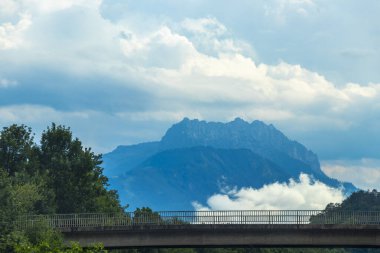 Dağ manzarası dağları yeşil tarlalar orman bulutları ve mavi gökyüzü Alpler Vorarlberg Avusturya.