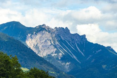 Dağ manzarası dağları yeşil tarlalar orman bulutları ve mavi gökyüzü Alpler Vorarlberg Avusturya.