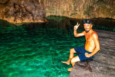 Erkek tur rehberi, Tulum Quintana Roo Mexico 'daki Yaxmulito mezarlığında turkuaz yeşil suda yüzüyor ve şnorkelle yüzüyor..