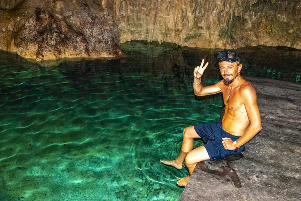 Erkek tur rehberi, Tulum Quintana Roo Mexico 'daki Yaxmulito mezarlığında turkuaz yeşil suda yüzüyor ve şnorkelle yüzüyor..