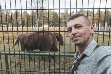 Bielaviezskaja Pusca Ulusal Parkı Bialowieza Ormanı Kamyanyets İlçe Brest Bölgesi 'nde bizon bizonlarıyla yakışıklı erkek turist..
