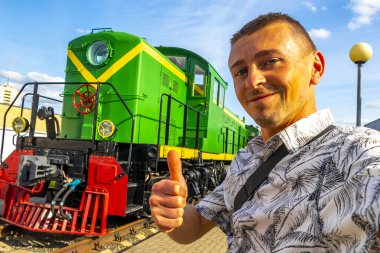 Klasik antika antika trenli yakışıklı erkek turist Leninskiy Rayon Brest Belarus 'taki Demiryolu Mühendislik Müzesi' nde buharlı lokomotifler eğitiyor..