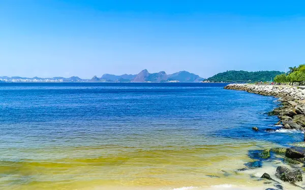 Güzel manzara Panorama Sahili Su Dalgaları Kayalar Dağlar ve Flamengo Plajı 'ndan Niteroi Tepeleri Rio de Janeiro Brezilya.
