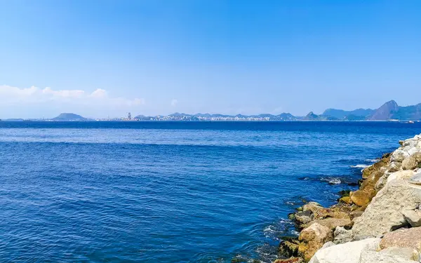 Güzel manzara Panorama Sahili Su Dalgaları Kayalar Dağlar ve Flamengo Plajı 'ndan Niteroi Tepeleri Rio de Janeiro Brezilya.