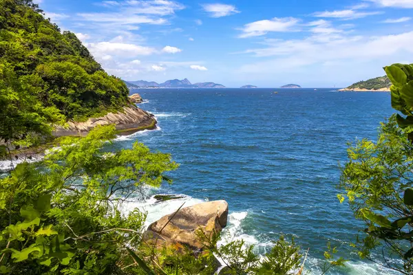 Rio de Janeiro Eyaleti Rio de Janeiro Brezilya 'da, Urca Red Beach Tropikal Cenneti Mavi Turkuaz Su Dalgaları Palmiye Ağaçları Kayalık Tepeler Kayalık Tepeler Sahil Kumu ve Beyaz Sahil Kumu.