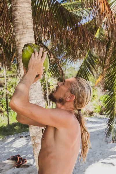 Playa del Carmen Quintana Roo Meksika sahilinde hindistan cevizi içen bir adam..