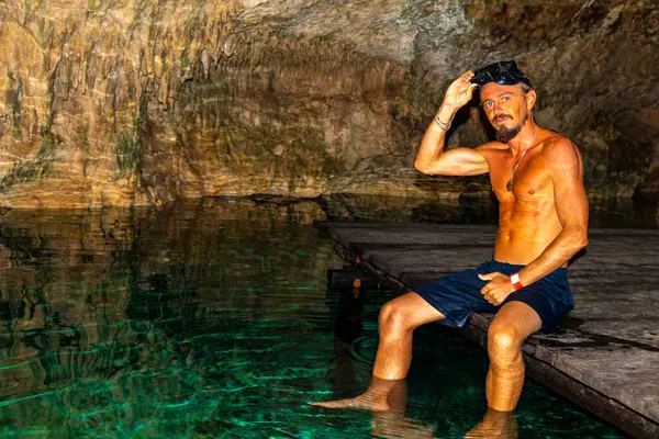 Erkek tur rehberi, Tulum Quintana Roo Mexico 'daki Yaxmulito mezarlığında turkuaz yeşil suda yüzüyor ve şnorkelle yüzüyor..