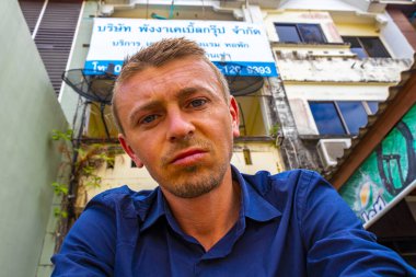 Yakışıklı erkek turist, Güneydoğu Asya 'da Khao Lak Amphoe Takua Pa Phang Nga Tayland' da bir otel girişinin önünde öfkeli bir şekilde bekliyor..