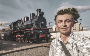 Klasik antika antika trenli yakışıklı erkek turist Leninskiy Rayon Brest Belarus 'taki Demiryolu Mühendislik Müzesi' nde buharlı lokomotifler eğitiyor..