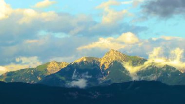 Yeşil tarlalar, orman bulutları, arabalar ve Alpler Vorarlberg Avusturya 'da mavi gökyüzü olan bir dağ manzarası boyunca sürüş yapmak..