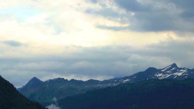 Yeşil tarlalar, orman bulutları, arabalar ve Alpler Vorarlberg Avusturya 'da mavi gökyüzü olan bir dağ manzarası boyunca sürüş yapmak..