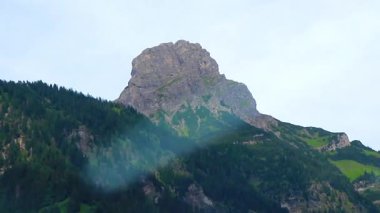 Yeşil tarlalar, orman bulutları, arabalar ve Alpler Vorarlberg Avusturya 'da mavi gökyüzü olan bir dağ manzarası boyunca sürüş yapmak..