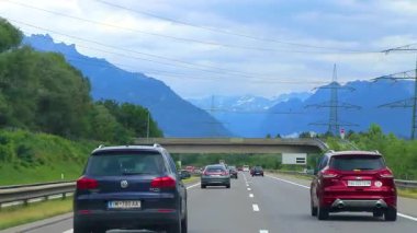 Alps Vorarlberg Avusturya 12. Temmuz 2019 'da, yeşil tarlalar, arabalar ve Alpler Vorarlberg Avusturya' da mavi gökyüzü olan otoyol üzerindeki bir dağ manzarası dağlarının içinden geçerken,.