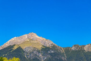 Dağ ve Alp tepeleri manzara dağları ve kayalar yeşil tarlalar ormanlar köknar ağaçları doğa ve mavi gökyüzü Alp Imst Tyrol Avusturya.