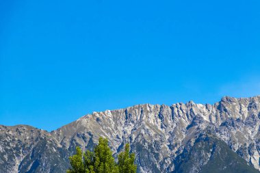 Dağ ve Alp tepeleri manzara dağları ve kayalar yeşil tarlalar ormanlar köknar ağaçları doğa ve mavi gökyüzü Alp Imst Tyrol Avusturya.