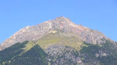 Dağ ve Alp tepeleri manzara dağları ve kayalar yeşil tarlalar ormanlar köknar ağaçları doğa ve mavi gökyüzü Alp Imst Tyrol Avusturya.