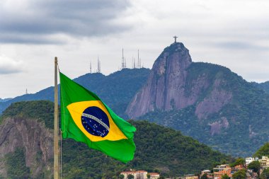 Kurtarıcı Cristo Redentor heykeli ve Corcovado dağ tepesinde Brezilya Bayrağı ve Alto da Boa Vista Brezilya manzaralı panorama.