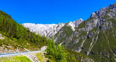 Dağ ve Alp Tepesi 'ndeki yollar dağlar ve kayalar yeşil tarlalarla kaplı manzaralar ormanlar köknar ağaçları ve Alpler' deki mavi gökyüzü Tyrol Avusturya.