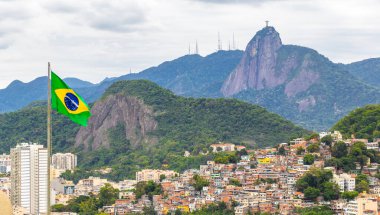 Kurtarıcı Cristo Redentor heykeli ve Corcovado dağ tepesinde Brezilya Bayrağı ve Alto da Boa Vista Brezilya manzaralı panorama.