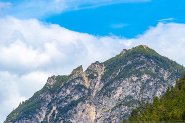 Dağ ve Alp Tepesi manzara dağları ve kayalar yeşil tarlalarla manzara manzarası çam ağaçları doğa ve Alpler 'deki bulutlu mavi gökyüzü Tyrol Avusturya.