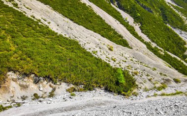 Yaz mevsiminde dağların zirvesinden düşen tehlikeli kayalar ve taş çığ Alplerdeki mavi gökyüzü Tyrol Avusturya.