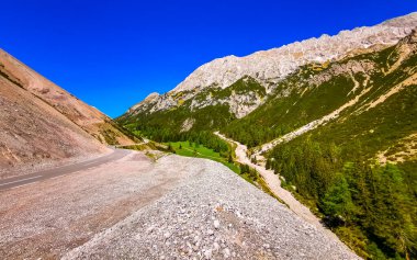 Dağ ve Alp Tepesi 'ndeki yollar dağlar ve kayalar yeşil tarlalarla kaplı manzaralar ormanlar köknar ağaçları ve Alpler' deki mavi gökyüzü Tyrol Avusturya.