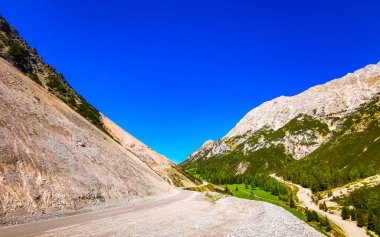 Dağ ve Alp Tepesi 'ndeki yollar dağlar ve kayalar yeşil tarlalarla kaplı manzaralar ormanlar köknar ağaçları ve Alpler' deki mavi gökyüzü Tyrol Avusturya.