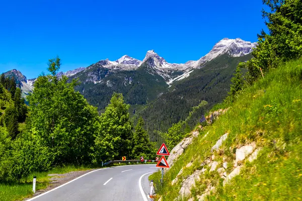 Dağ ve Alp Tepesi 'ndeki yollar dağlar ve kayalar yeşil tarlalarla kaplı manzaralar ormanlar köknar ağaçları ve Alpler' deki mavi gökyüzü Tyrol Avusturya.
