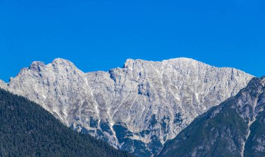 Dağ ve Alp tepeleri manzara dağları ve kayalar yeşil tarlalar ormanlar köknar ağaçları doğa ve mavi gökyüzü Alp Imst Tyrol Avusturya.