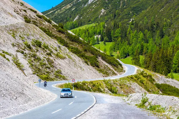 Dağ ve Alp Tepesi 'ndeki yollar dağlar ve kayalar yeşil tarlalarla kaplı manzaralar ormanlar köknar ağaçları ve Alpler' deki mavi gökyüzü Tyrol Avusturya.