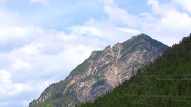 Dağ ve Alp Tepesi manzara dağları ve kayalar yeşil tarlalarıyla manzara ormanı köknar ağaçları doğa ve Alpler 'deki bulutlu mavi gökyüzü Tyrol Avusturya.