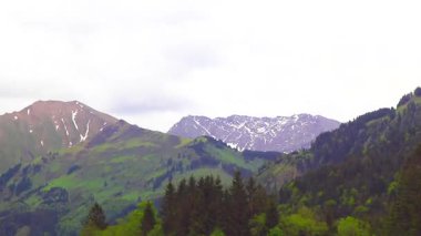 Dağ ve dağlık arazi dağları karla kaplı kaya ve tepeler ve manzaralar ve Alpler 'deki bulutlu mavi gökyüzü Reutte Tyrol Avusturya.