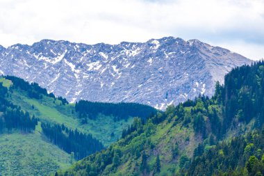 Dağ ve dağlık arazi dağları karla kaplı kaya ve tepeler ve manzaralar ve Alpler 'deki bulutlu mavi gökyüzü Reutte Tyrol Avusturya.