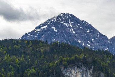 Dağ ve dağlık arazi dağları karla kaplı kaya ve tepeler ve manzaralar ve Alpler 'deki bulutlu mavi gökyüzü Reutte Tyrol Avusturya.