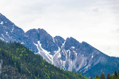 Dağ ve dağlık arazi dağları karla kaplı kaya ve tepeler ve manzaralar ve Alpler 'deki bulutlu mavi gökyüzü Reutte Tyrol Avusturya.