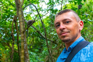 Yakışıklı turist, yeşil tropikal yağmur ormanlarında Marmoset Maymunlarıyla selfie çekiyor Rio de Janeiro Eyaleti Rio de Janeiro Brezilya 'da bir ağaca tırmanıyor..