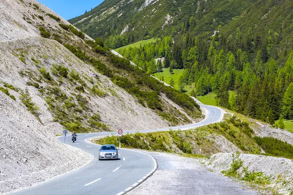 Dağ ve Alp Tepesi 'ndeki yollar dağlar ve kayalar yeşil tarlalarla kaplı manzaralar ormanlar köknar ağaçları ve Alpler' deki mavi gökyüzü Tyrol Avusturya.