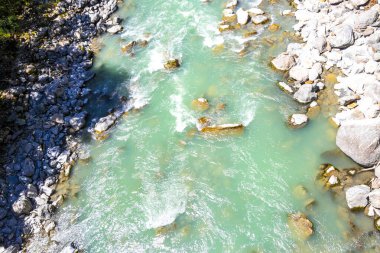 Turkuaz mavi ve yeşil nehir buharı ve köprü taşlı şelale hanı. Çimen ağaçları, doğa ve dağ manzarası. Alplerde uçan Landeck Tyrol Avusturya..