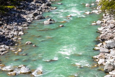 Turkuaz mavi ve yeşil nehir buharı ve köprü taşlı şelale hanı. Çimen ağaçları, doğa ve dağ manzarası. Alplerde uçan Landeck Tyrol Avusturya..