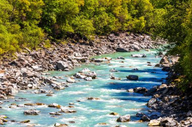 Turkuaz mavi ve yeşil nehir buharı ve köprü taşlı şelale hanı. Çimen ağaçları, doğa ve dağ manzarası. Alplerde uçan Landeck Tyrol Avusturya..
