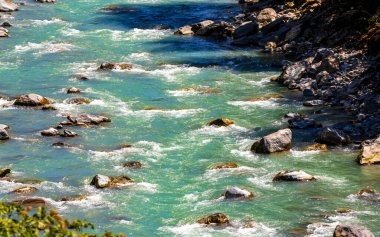 Turkuaz mavi ve yeşil nehir buharı ve köprü taşlı şelale hanı. Çimen ağaçları, doğa ve dağ manzarası. Alplerde uçan Landeck Tyrol Avusturya..