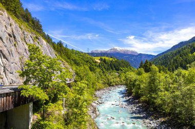 Turkuaz mavi ve yeşil nehir buharı ve köprü taşlı şelale hanı. Çimen ağaçları, doğa ve dağ manzarası. Alplerde uçan Landeck Tyrol Avusturya..