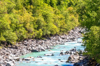 Turkuaz mavi ve yeşil nehir buharı ve köprü taşlı şelale hanı. Çimen ağaçları, doğa ve dağ manzarası. Alplerde uçan Landeck Tyrol Avusturya..