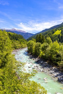 Turkuaz mavi ve yeşil nehir buharı ve köprü taşlı şelale hanı. Çimen ağaçları, doğa ve dağ manzarası. Alplerde uçan Landeck Tyrol Avusturya..