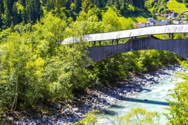 Turkuaz mavi ve yeşil nehir buharı ve köprü taşlı şelale hanı. Çimen ağaçları, doğa ve dağ manzarası. Alplerde uçan Landeck Tyrol Avusturya..